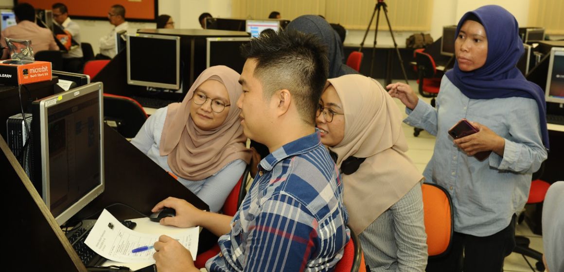 Teachers smiling and working on a computer.